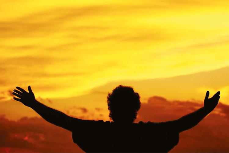 Pessoa no por do sol com os braços abertos