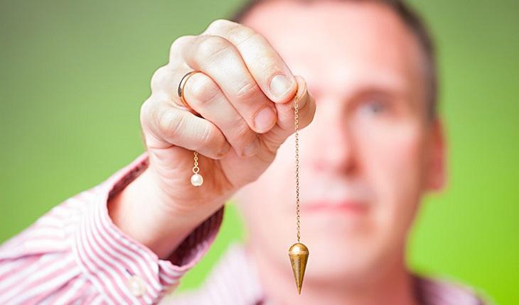 homem segurando pingente em sessão de hipnose