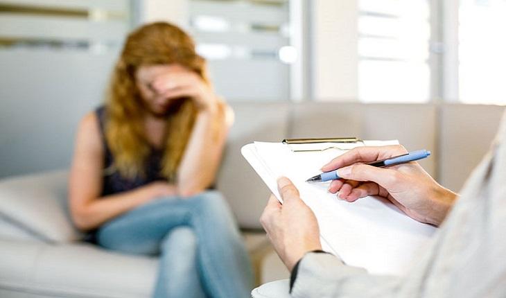 mulher triste e sentada, sendo consultada por um psicólogo
