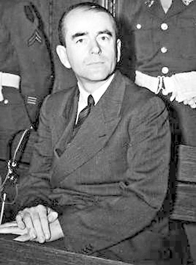albert speer sentado de terno observando camera