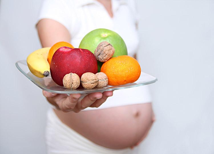 Grávida segurando prato de frutas
