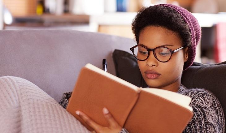 Mulher deitada escrevendo em um livro de estudos