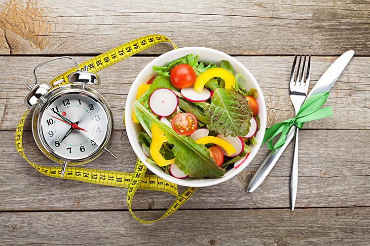 alimentos-recipiente-fita-metrica-garfo-faca-despertador-mesa