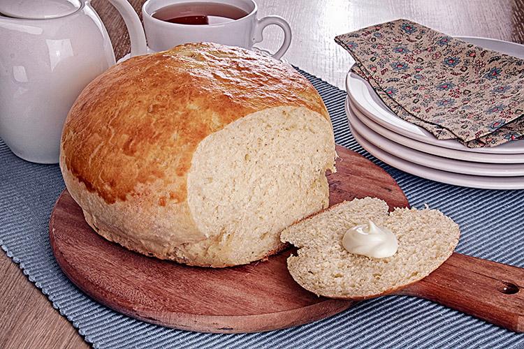 Pão de mandioca com uma fatia cortada sobre uma tábua.