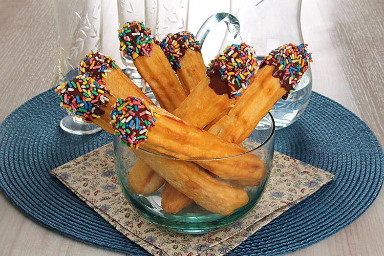 Churros com chocolate e confeitos dentro de um potinho de vidro