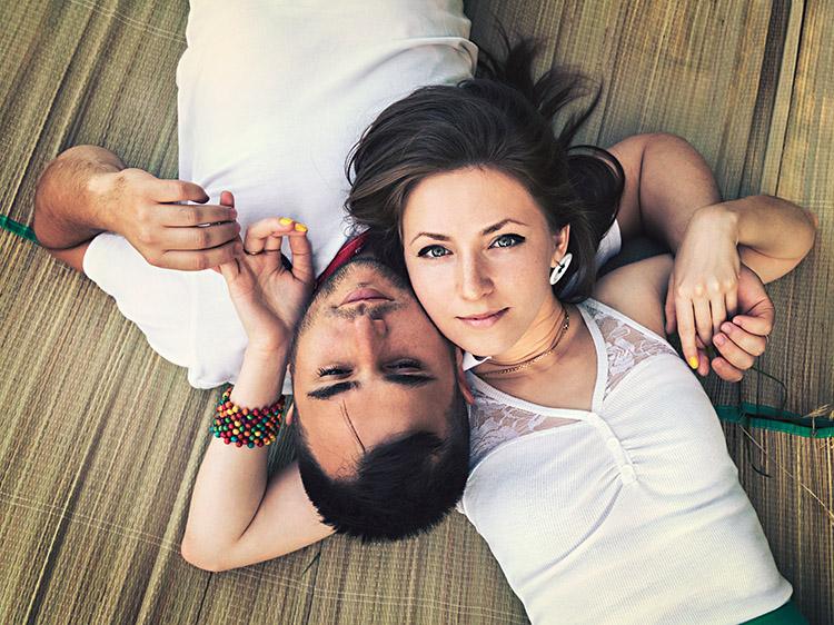 Casal em harmonia, deitado no chão com as mãos dadas