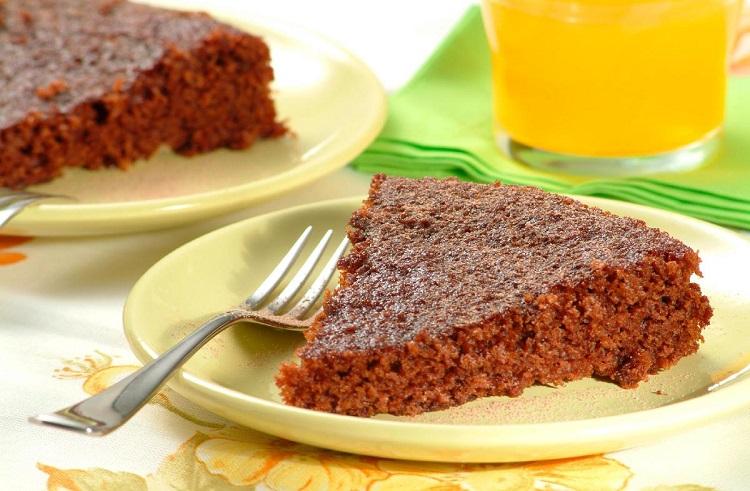 Pedaço de bolo de chocolate sem ovo em cima de uma prato amarelo