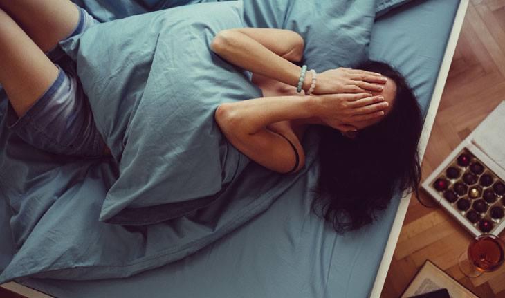 mulher deitada na cama triste