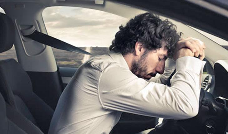 Homem deitado no volante do carro