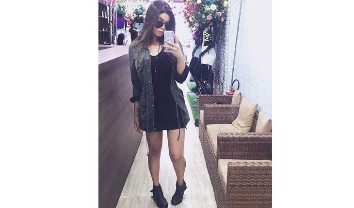 mulher com vestido preto e camisa jeans com um coturno