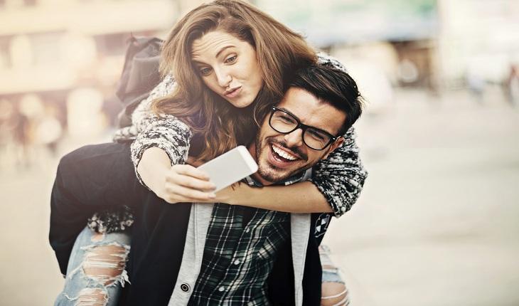 Moça abraçando namorado e tirando selfie