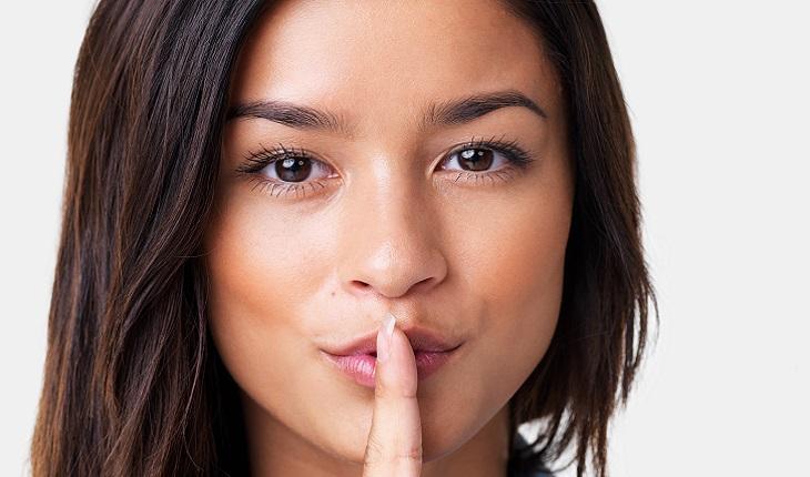 Mulher com dedo na boca fazendo sinal de silêncio. Como ser mais concentrada