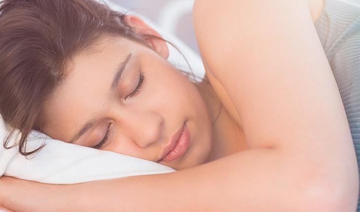Mulher morena dormindo tranquila na cama. como ser mais concentrada