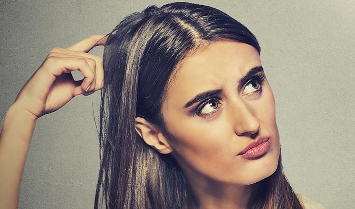 Mulher, pensando, com mão na cabeça, olhando para a lâmpada. Como ser mais concentrada
