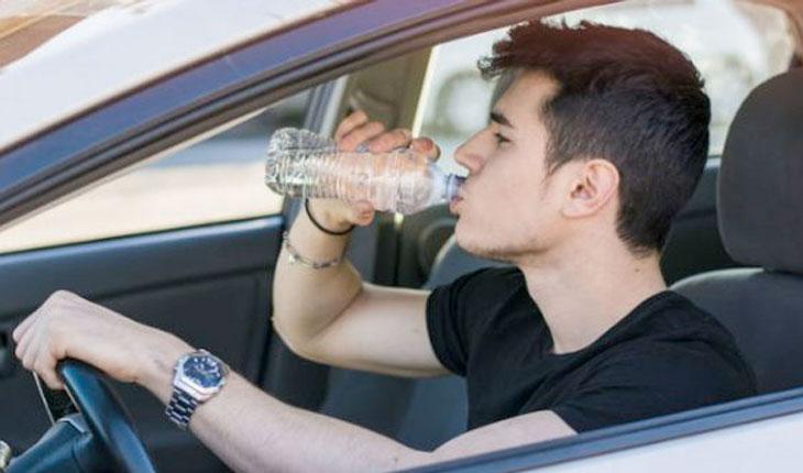 Pessoa segurando garrafa de água no volante