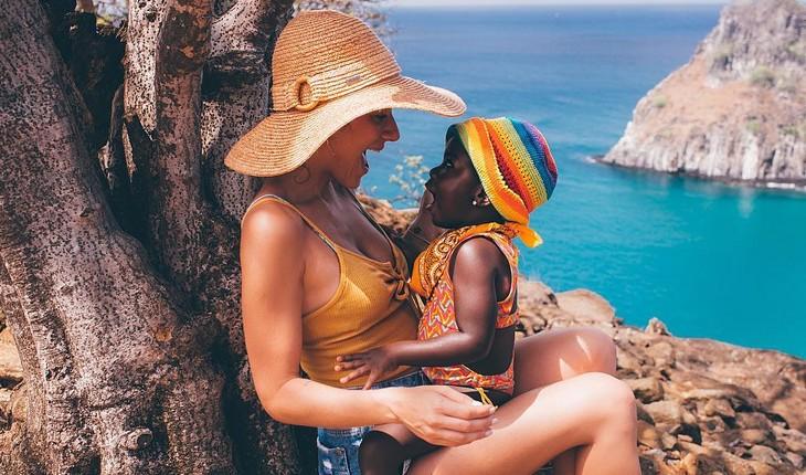 titi sentada no colo da mãe em uma praia