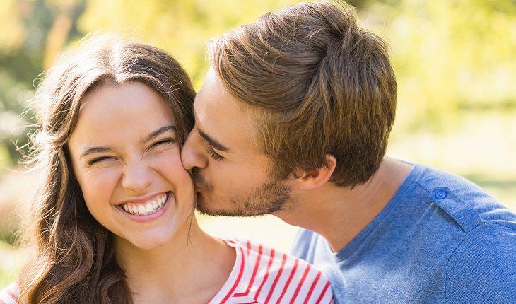 Rapaz beijando namorada no rosto mostrando sua saudade.