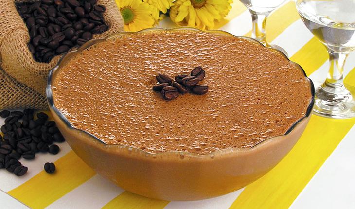 Imagem de mousse cappuccino light, sobre uma mesa. Ao redor, para enfeitar, um saco e grãos de café espalhados.