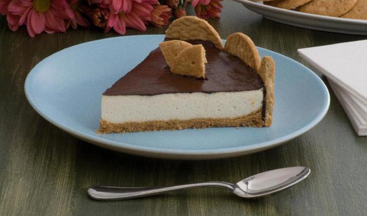 Imagem de torta holandesa light, sobre um prato branco. Ao lado uma colher, em cima de uma mesa de madeira.