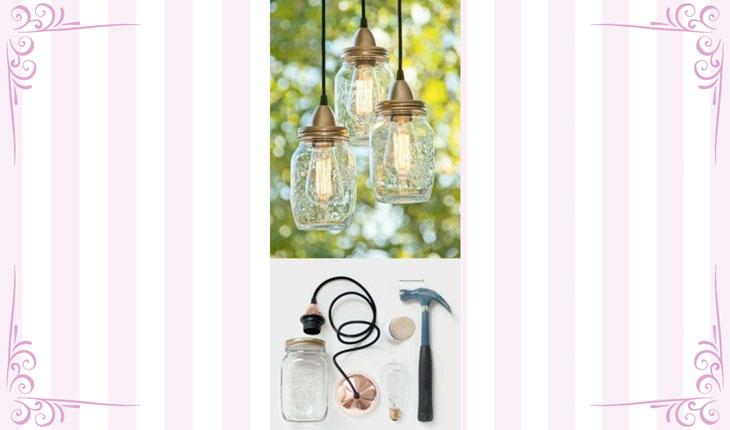 Na imagem há uma foto centralizada de luminárias penduradas feitas com potes de vidro. Dentro de cada um deles há lâmpadas que estão acesas. São 3 luminárias. Ao redor há uma moldura branca com detalhes em rosa.