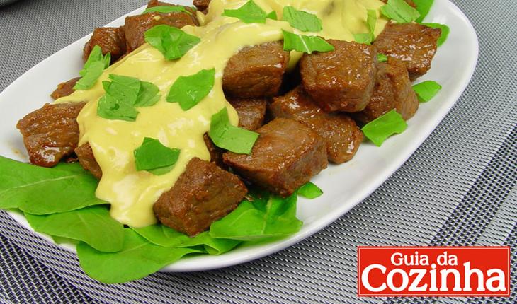 Foto da receita de picadinho de carne com rúcula em uma travessa.