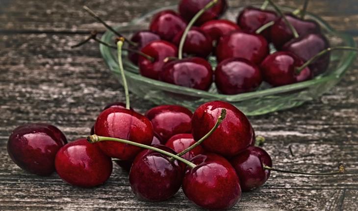cerejas dentro e fora de uma tigela verde