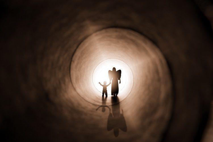 Espíritos protetores. Criança e um anjo caminhando para uma luz