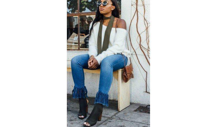 Mulher sentada com calça jeans com franja.