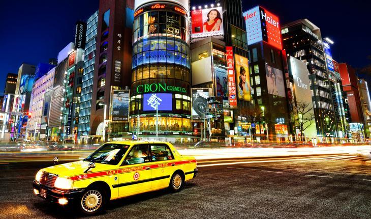 Táxi amarelo em metrópole com prédios coloridos